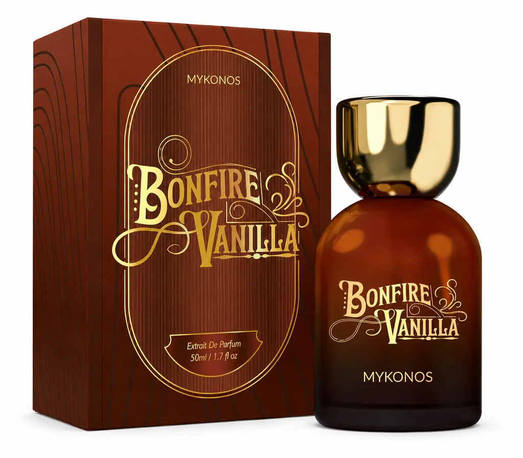 Mykonos Bonfire Vanilla Eau de Parfum bottle with a gold cap next to its brown wood-grain textured packaging box, both featuring gold lettering. Mykonos Bonfire Vanilla Extrait de Parfum 50ml perfume bottle – cozy smoky woods, warm toasted vanilla, and sweet amber gourmand fragrance for men and women
