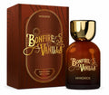 Mykonos Bonfire Vanilla Eau de Parfum bottle with a gold cap next to its brown wood-grain textured packaging box, both featuring gold lettering. Mykonos Bonfire Vanilla Extrait de Parfum 50ml perfume bottle – cozy smoky woods, warm toasted vanilla, and sweet amber gourmand fragrance for men and women
