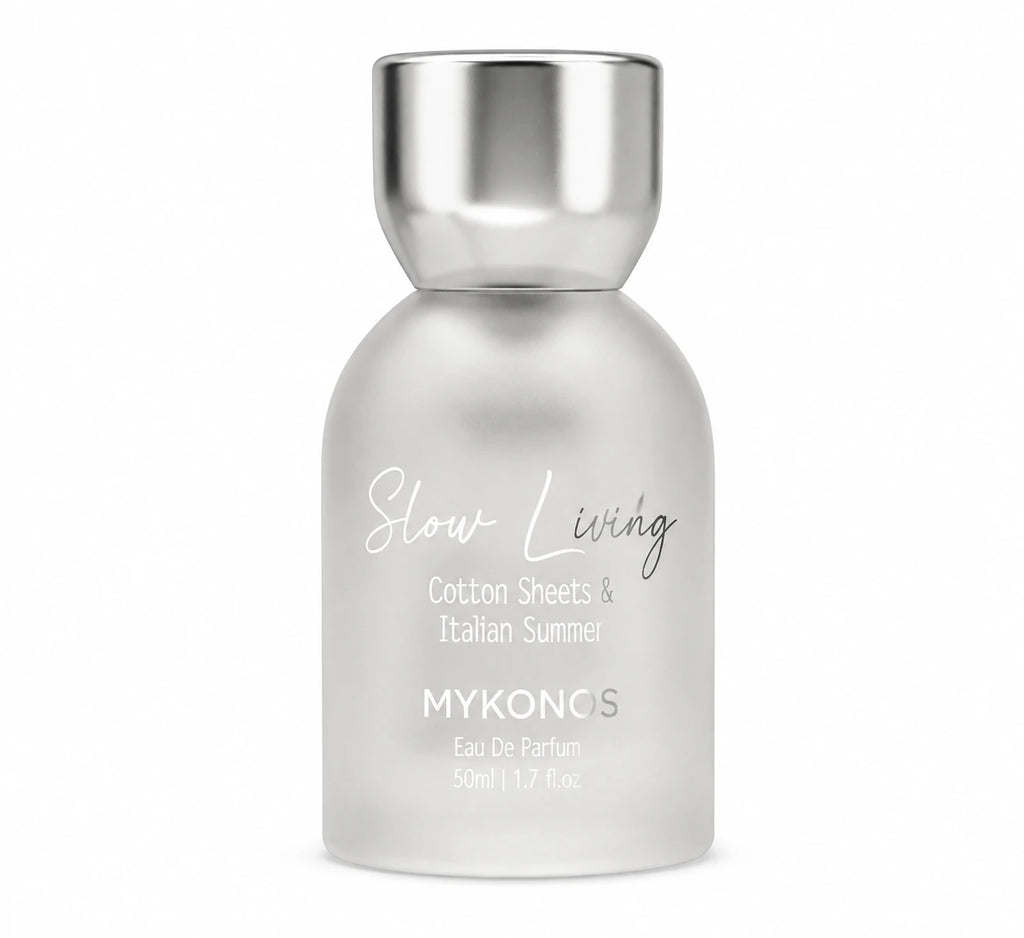 A 50ml bottle of MYKONOS Slow Living Cotton Sheets & Italian Summer Eau De Parfum, featuring a frosted glass body and a metallic silver cap, set against a plain white background. Calming green tea, soft florals, and soothing woody musk fragrance for men and women